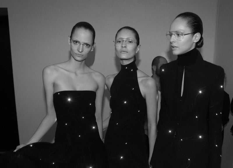 Drei Models in schwarzer Abendgarderobe hinter den Kulissen der Akris Modenschau in Paris.