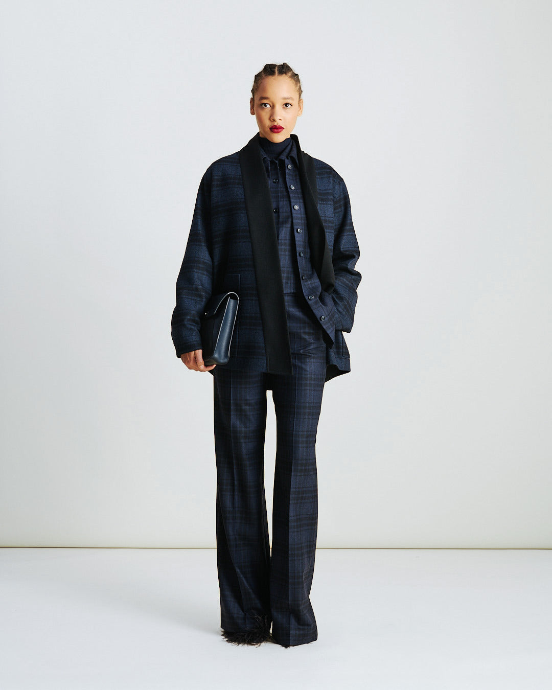 Akris Fall/Winter look featuring an oversized plaid wool shirt jacket layered over matching flannel trousers in denim black tones — a modern interpretation of relaxed tailoring with timeless sophistication.