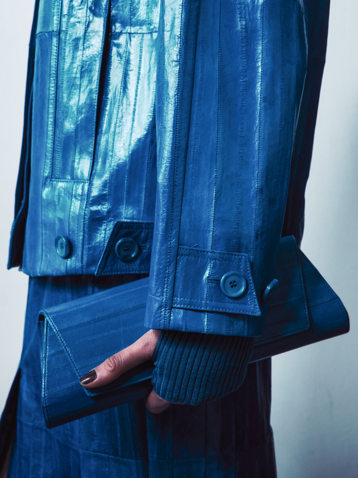 Eine strukturierte smaragdgrüne Handtasche mit Henkel, die eine markante Weboptik und einen klaren, geometrischen Verschluss aufweist.