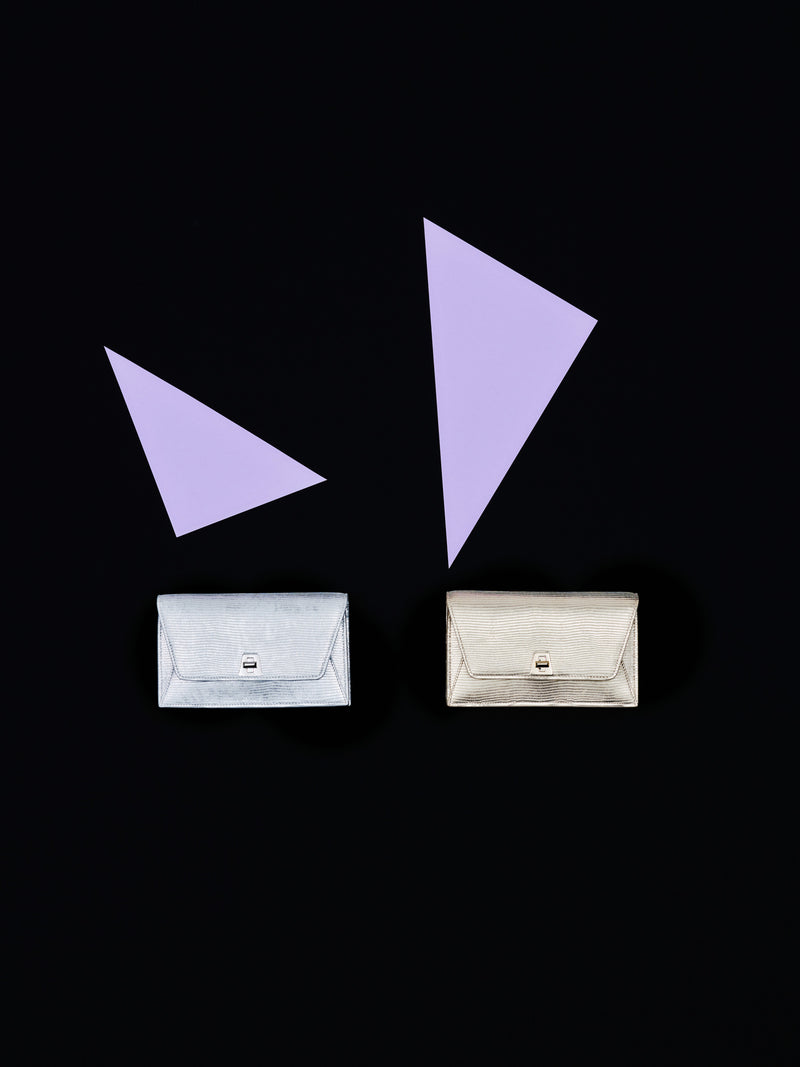 Erleben Sie den abendlichen Glamour der Akris Pre-Fall Kollektion mit den eleganten Anouk Clutches in markantem Metallic-Silber und -Gold. Vor einem minimalistischen, schwarzen Hintergrund mit präzisen, lavendelfarbenen geometrischen Akzenten strahlen diese Luxus-Accessoires moderne Raffinesse aus. Verleihen Sie Ihrem Look zeitlose Schweizer Schneiderkunst.