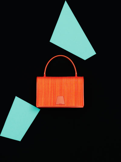 Erleben Sie die strukturierte Eleganz der Akris Pre-Fall Kollektion mit der anspruchsvollen Alice Handtasche aus edlem Rosshaar (Horsehair). Kunstvoll inszeniert vor einem minimalistischen, schwarzen Hintergrund mit leuchtend roten, geometrischen Akzenten, setzt dieses Luxus-Accessoire ein exklusives Statement. Entdecken Sie einzigartige Materialien und erstklassige Schweizer Handwerkskunst.