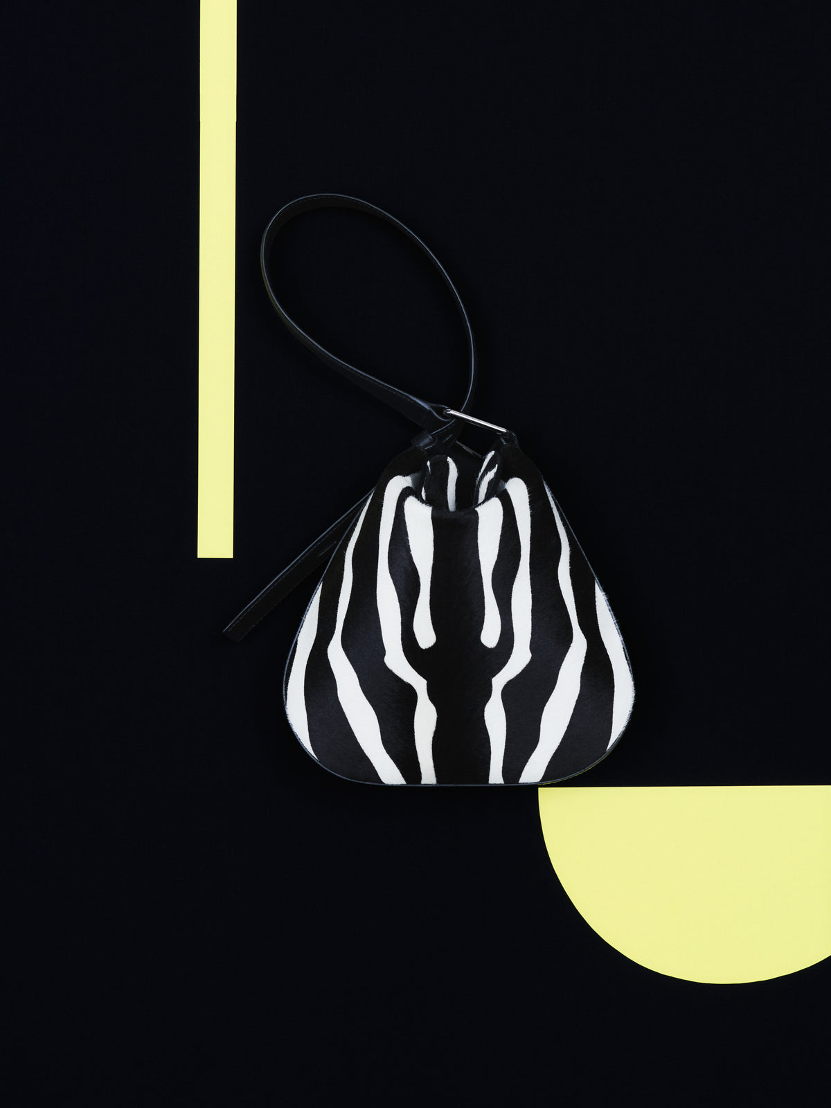 Erleben Sie die ausdrucksstarke Eleganz der Akris Pre-Fall Kollektion mit der anspruchsvollen Anna Hobo Handtasche im markanten Zebra-Look. Stilvoll inszeniert vor einem minimalistischen, schwarzen Hintergrund mit hellgelben geometrischen Akzenten, besticht dieses Luxus-Accessoire durch seine moderne, weiche Silhouette. Entdecken Sie erstklassige Schweizer Handwerkskunst.