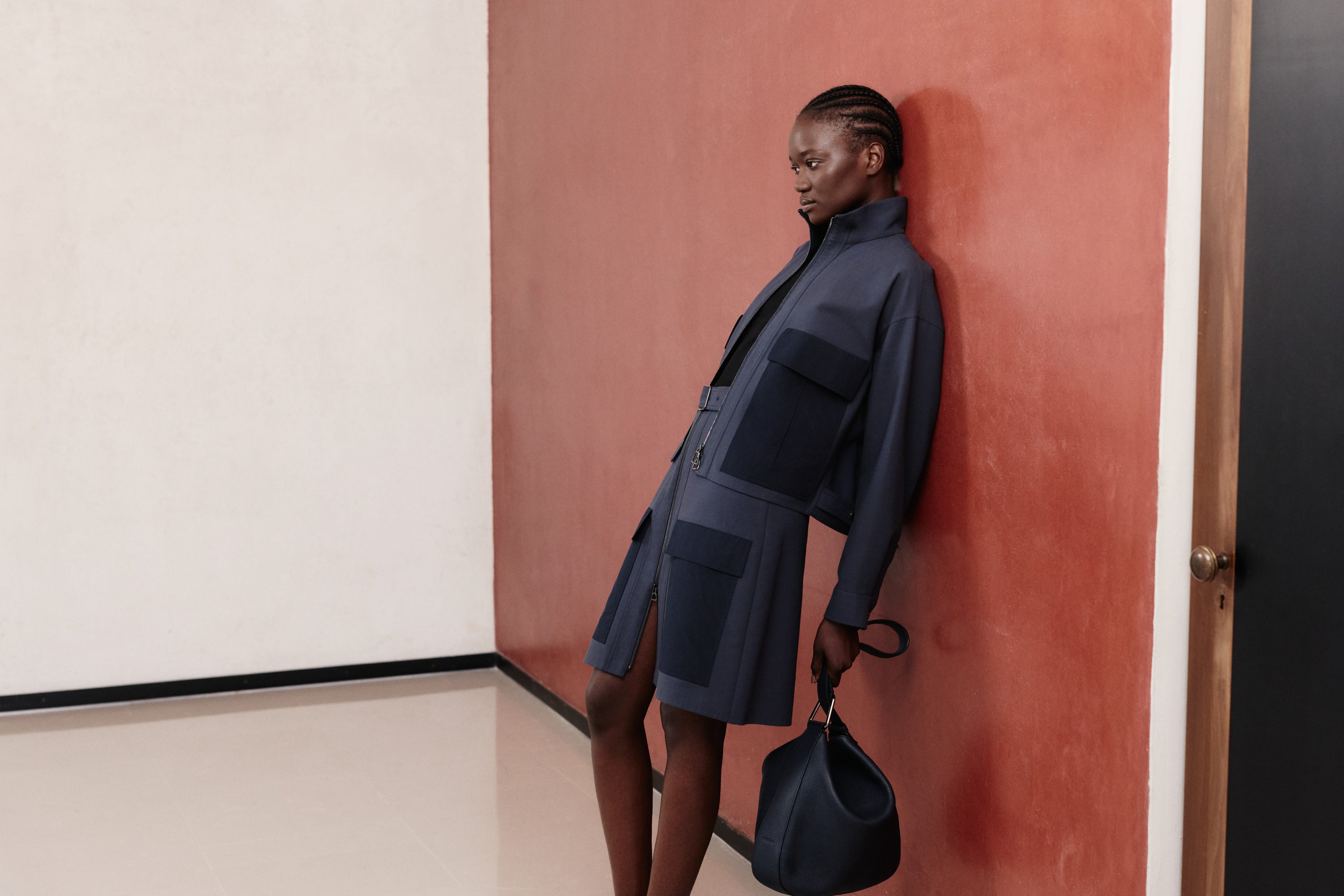 Erleben Sie den modernen Utility-Stil der Akris Pre-Fall Kollektion mit einer strukturierten Jacke-Rock-Kombination in tiefem Marineblau und markanten Taschen-Details. Ergänzt wird das monochrome Ensemble durch eine weiche, luxuriöse Handtasche für einen zeitgemäßen Look. Entdecken Sie innovative Schneiderkunst und erstklassiges Schweizer Design.