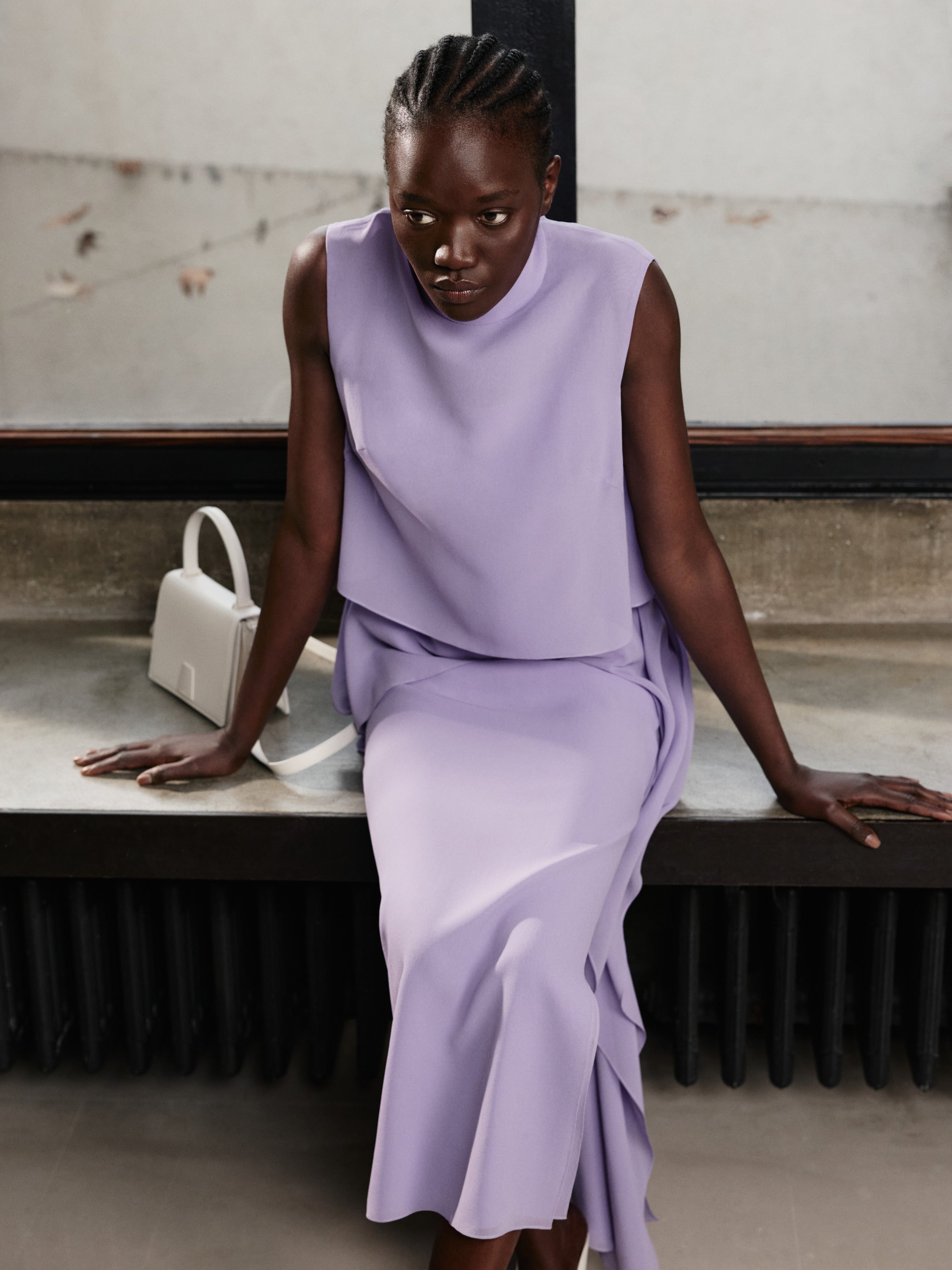 Erleben Sie mühelose Eleganz mit der Akris Pre-Fall Kollektion in einem zarten, monochromen Glyzinien-Violett. Ergänzen Sie das fließend drapierte Ensemble mit der minimalistischen, weißen Alice Handtasche. Entdecken Sie die perfekte Balance aus modernem Schneiderhandwerk und zeitlosem Luxus.