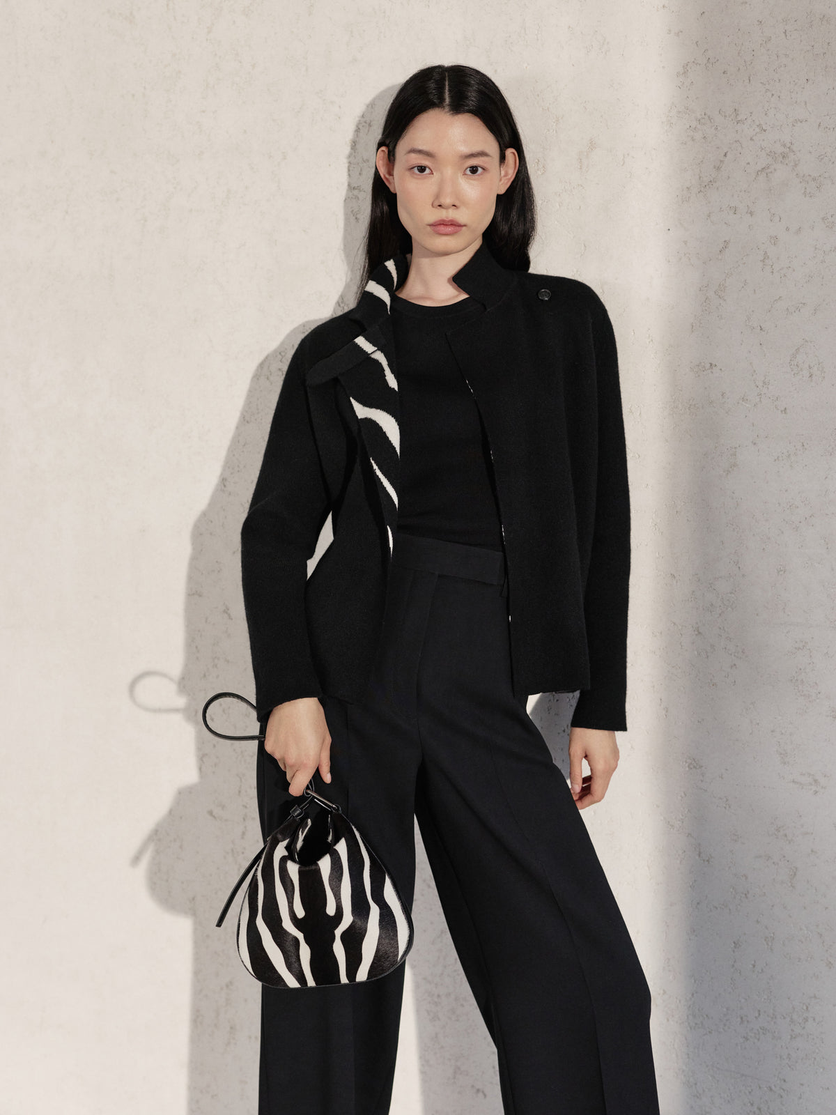 Entdecken Sie die raffinierte Vielseitigkeit della Akris Pre-Fall Kollektion in einem eleganten schwarzen Ensemble mit dezentem Zebra-Akzent am Kragen. Setzen Sie ein stilvolles Statement mit der passenden Anna Hobo Handtasche im ausdrucksstarken Zebra-Print. Erleben Sie modernes Design vereint mit zeitloser Schweizer Handwerkskunst.
