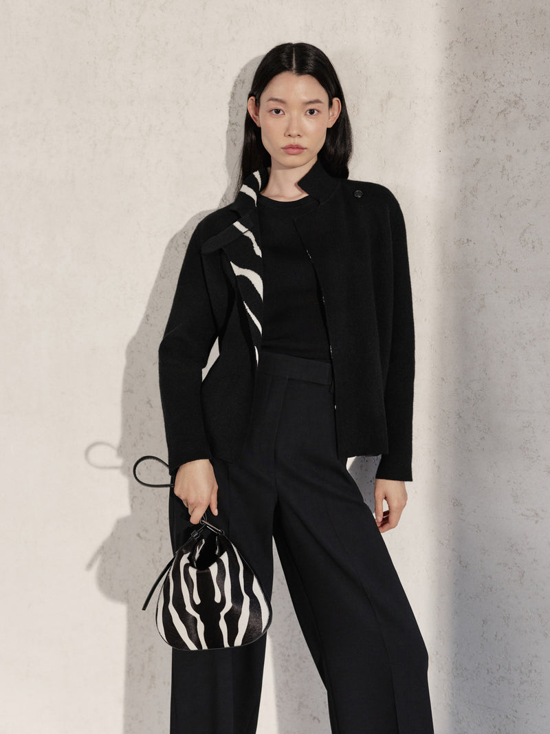 Entdecken Sie die raffinierte Vielseitigkeit della Akris Pre-Fall Kollektion in einem eleganten schwarzen Ensemble mit dezentem Zebra-Akzent am Kragen. Setzen Sie ein stilvolles Statement mit der passenden Anna Hobo Handtasche im ausdrucksstarken Zebra-Print. Erleben Sie modernes Design vereint mit zeitloser Schweizer Handwerkskunst.
