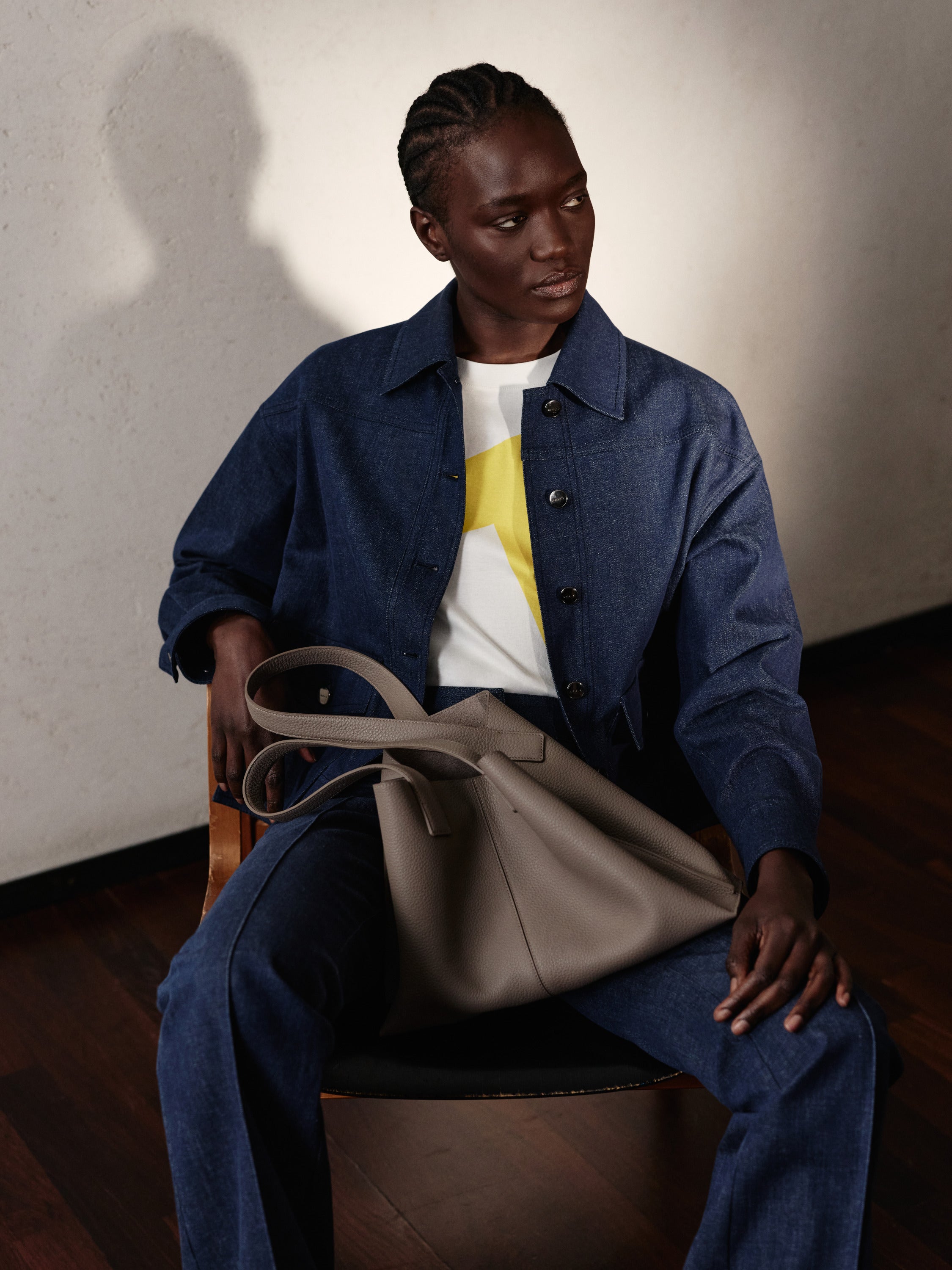 Erleben Sie den edlen Casual-Look der Akris Pre-Fall Kollektion mit einer hochwertigen Denim-Jacke und einem Oberteil mit leuchtend gelben Akzenten. Vollendet wird das moderne Ensemble durch die ikonische Ai Handtasche aus feinstem Leder in elegantem Taupe. Verleihen Sie Ihrem Alltagsstil zeitlose Schweizer Klasse.