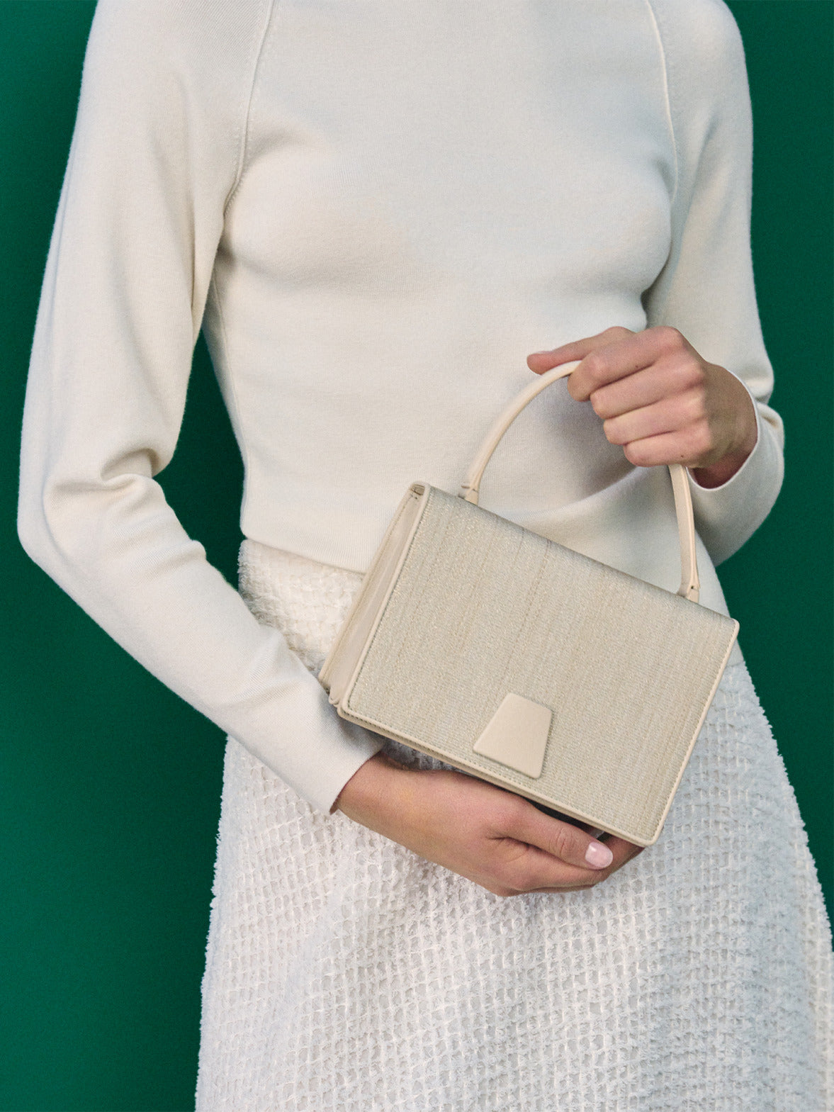 Akris Frühjahr/Sommer Handtasche in Trapezform aus strukturiertem beigem Gewebe. Fokus auf das edle Webmaterial, den minimalistischen Griff und den markanten architektonischen Verschluss.