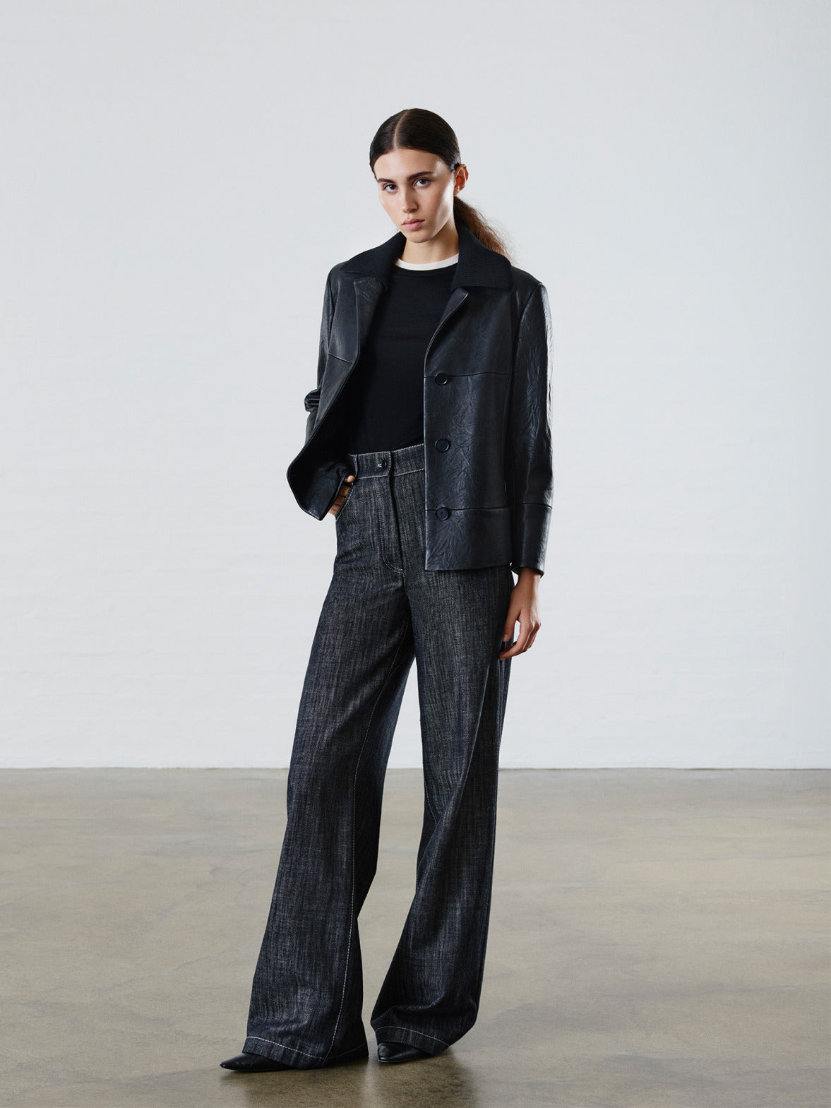 "Denim Vibes" Kampagne: Hochwertige schwarze Lederjacke mit Strickkragen kombiniert mit einer dunkelgrauen High-Waist-Jeans aus strukturierter Baumwolle.