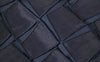 Model in einem dunkelblauen, transparenten Kleid mit Gittermuster aus der Akris Pre-Fall 2026 Kollektion, sitzend auf einer minimalistischen weißen Kommode. Moderne Luxus-Damenmode mit architektonischem Design und geometrischen Texturen.